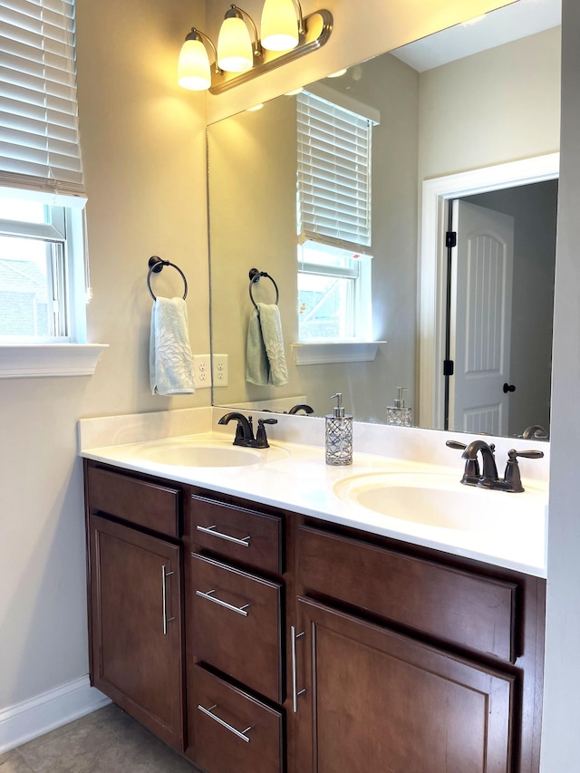 full bathroom with a sink, baseboards, and double vanity