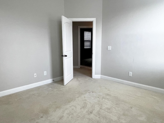 carpeted empty room featuring baseboards