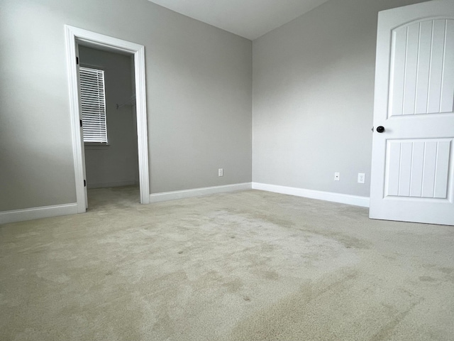 unfurnished bedroom with a spacious closet, baseboards, and carpet floors