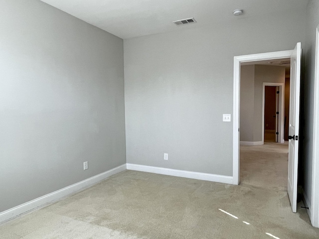 empty room featuring light colored carpet, visible vents, and baseboards