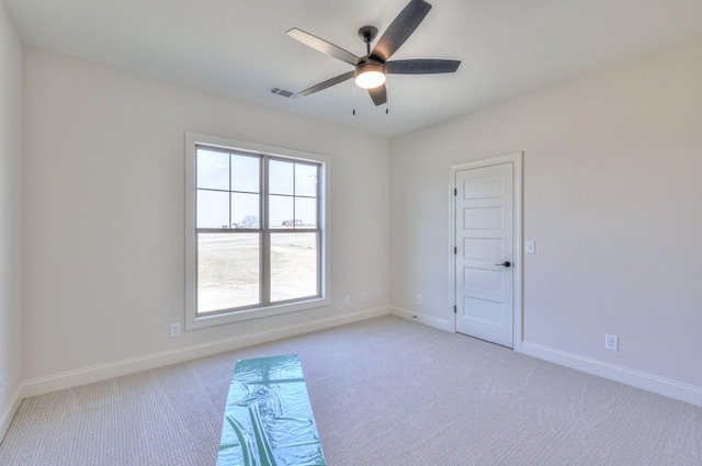 empty room featuring visible vents, baseboards, light colored carpet, and a ceiling fan