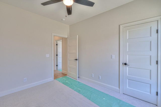 carpeted empty room with a ceiling fan and baseboards