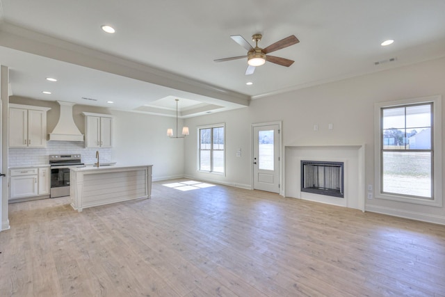 unfurnished living room with light wood-type flooring, visible vents, a sink, a fireplace, and baseboards