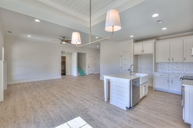 kitchen with visible vents, dishwasher, light countertops, decorative backsplash, and a sink