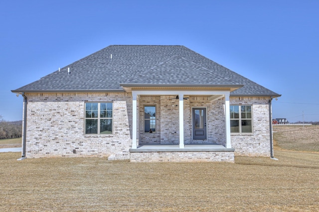 back of property with brick siding and a shingled roof