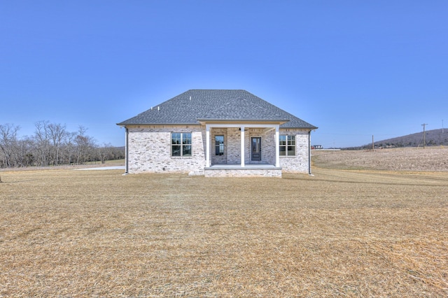 view of front of home featuring brick siding and roof with shingles