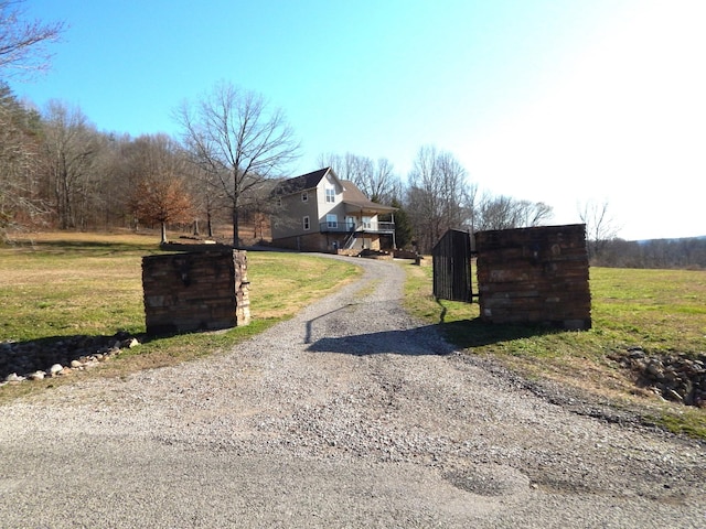 view of street with a gated entry and gravel driveway