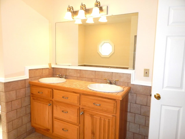 bathroom featuring a sink, a wainscoted wall, and tile walls