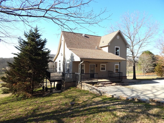 exterior space featuring a porch, a lawn, and roof with shingles