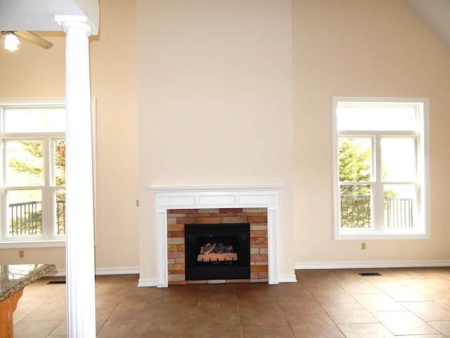 unfurnished living room featuring visible vents, baseboards, a fireplace, tile patterned floors, and high vaulted ceiling