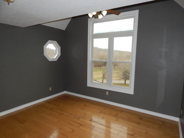 interior space with a textured ceiling, baseboards, lofted ceiling, and hardwood / wood-style floors