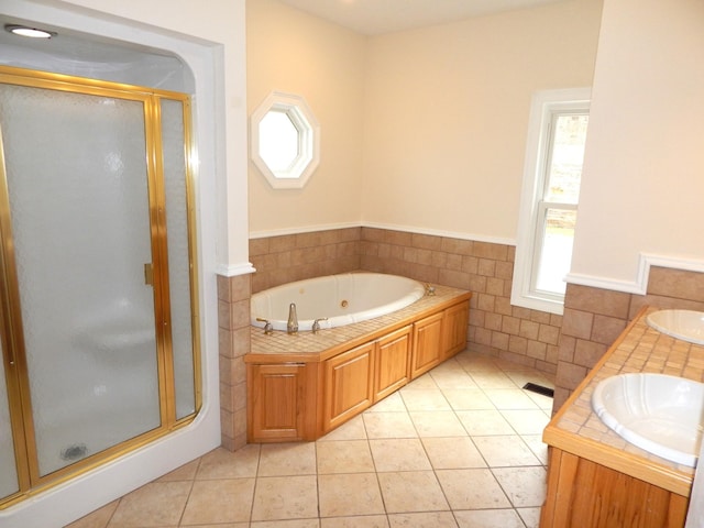 full bath featuring tile walls, plenty of natural light, tile patterned floors, and a sink