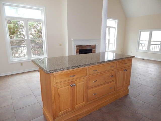 kitchen with stone countertops, lofted ceiling, open floor plan, and a fireplace