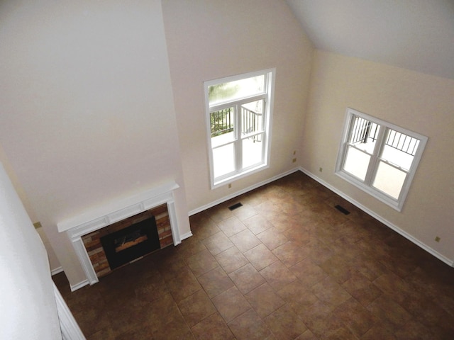 unfurnished living room with visible vents, baseboards, a fireplace, and vaulted ceiling