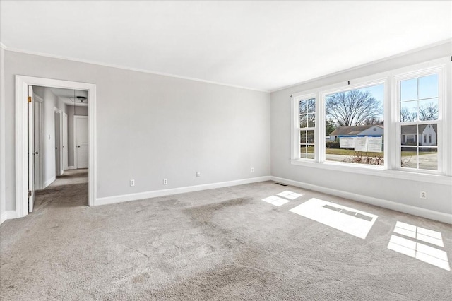 carpeted empty room with crown molding, visible vents, and baseboards