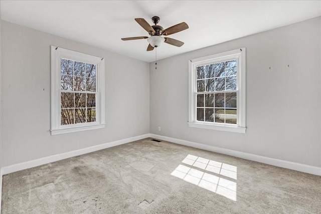 spare room with baseboards, carpet floors, visible vents, and ceiling fan