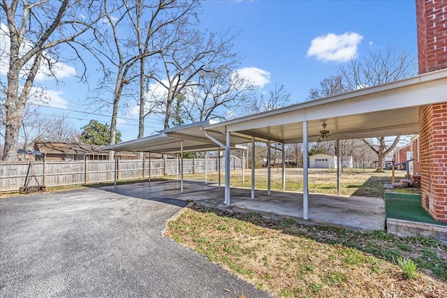 view of parking / parking lot featuring a carport, driveway, and fence