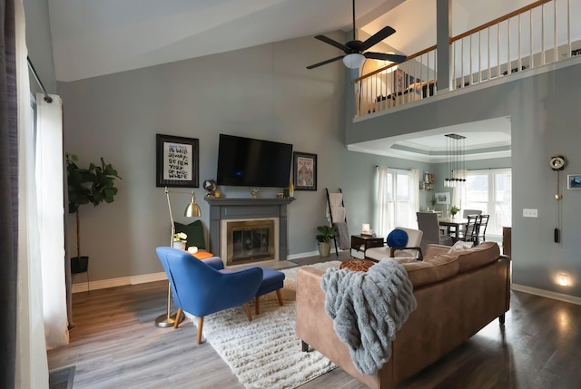 living area with a glass covered fireplace, visible vents, wood finished floors, and baseboards