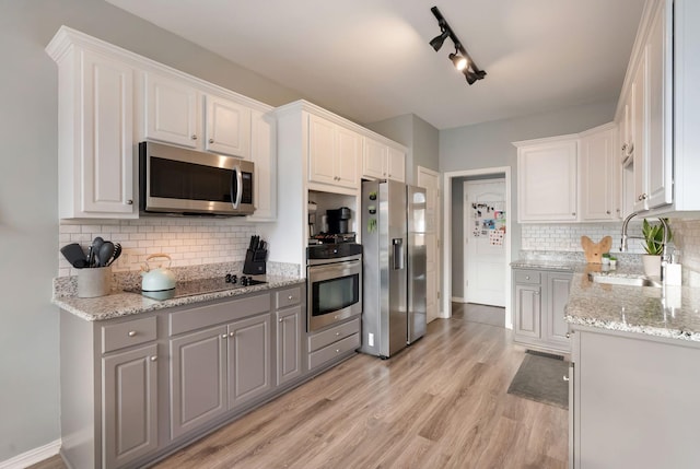 kitchen featuring backsplash, light wood-type flooring, white cabinets, stainless steel appliances, and a sink