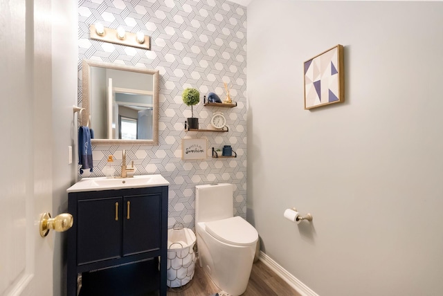 bathroom with toilet, vanity, baseboards, and wood finished floors