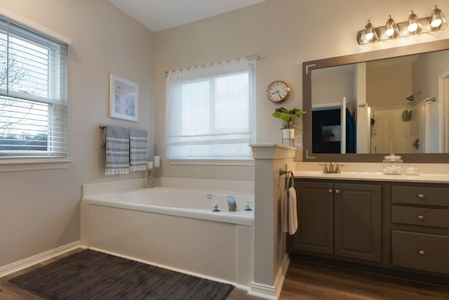 bathroom featuring a wealth of natural light, vanity, a shower, and a garden tub