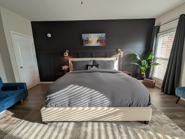 bedroom with a decorative wall, wood finished floors, and a wainscoted wall