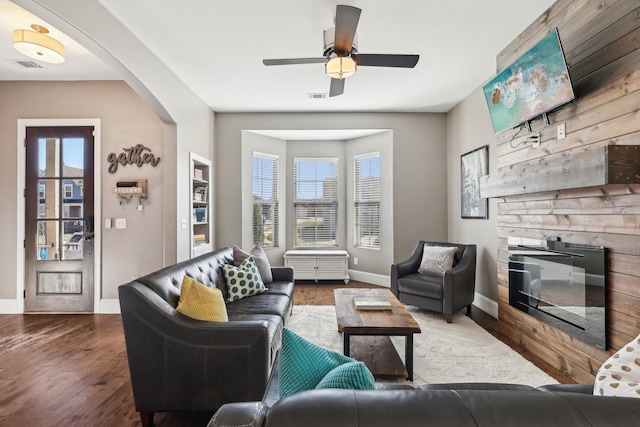 living room with visible vents, arched walkways, baseboards, and wood finished floors