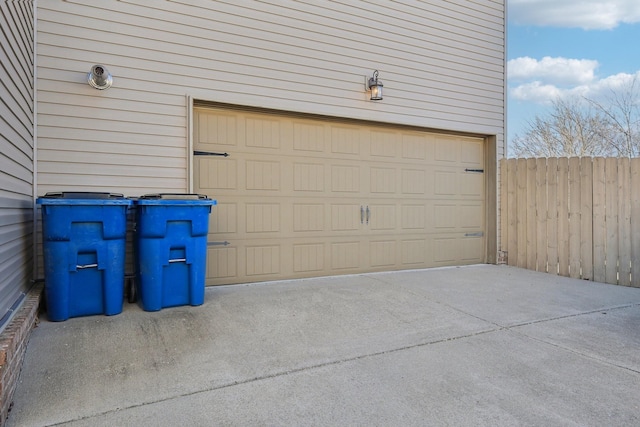 garage with concrete driveway and fence