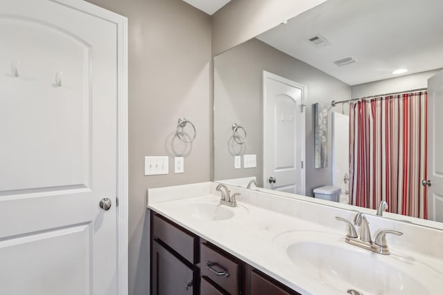 full bathroom with double vanity, visible vents, toilet, and a sink