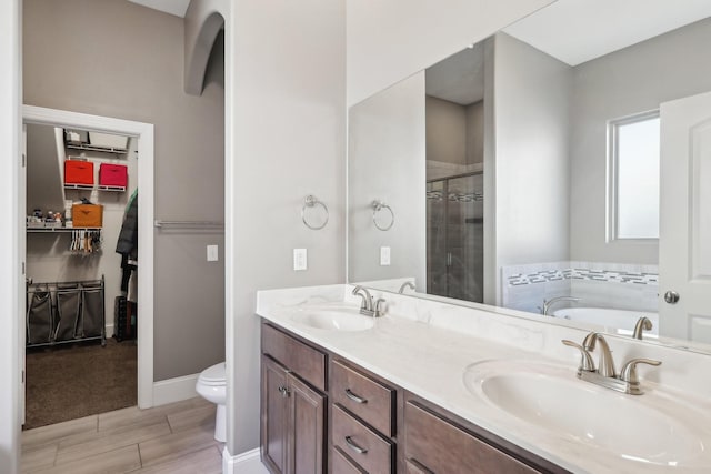 bathroom with double vanity, toilet, a stall shower, and a sink