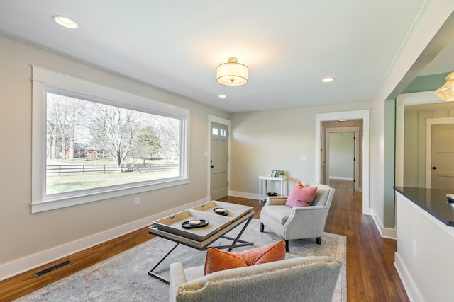 living area with dark wood finished floors, baseboards, and visible vents