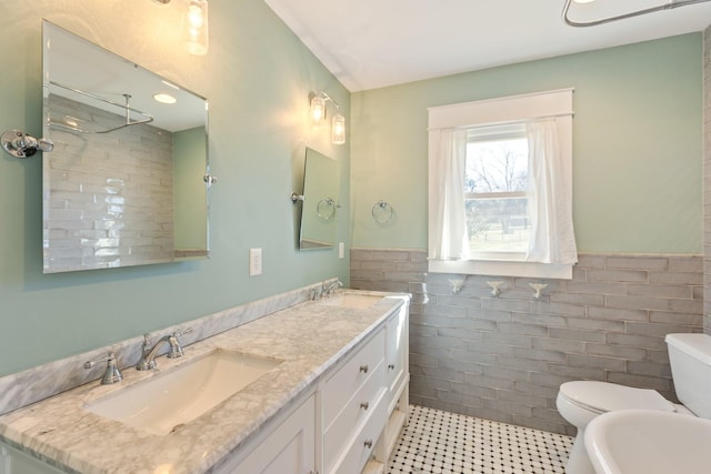 bathroom featuring tile walls, toilet, a wainscoted wall, and a sink