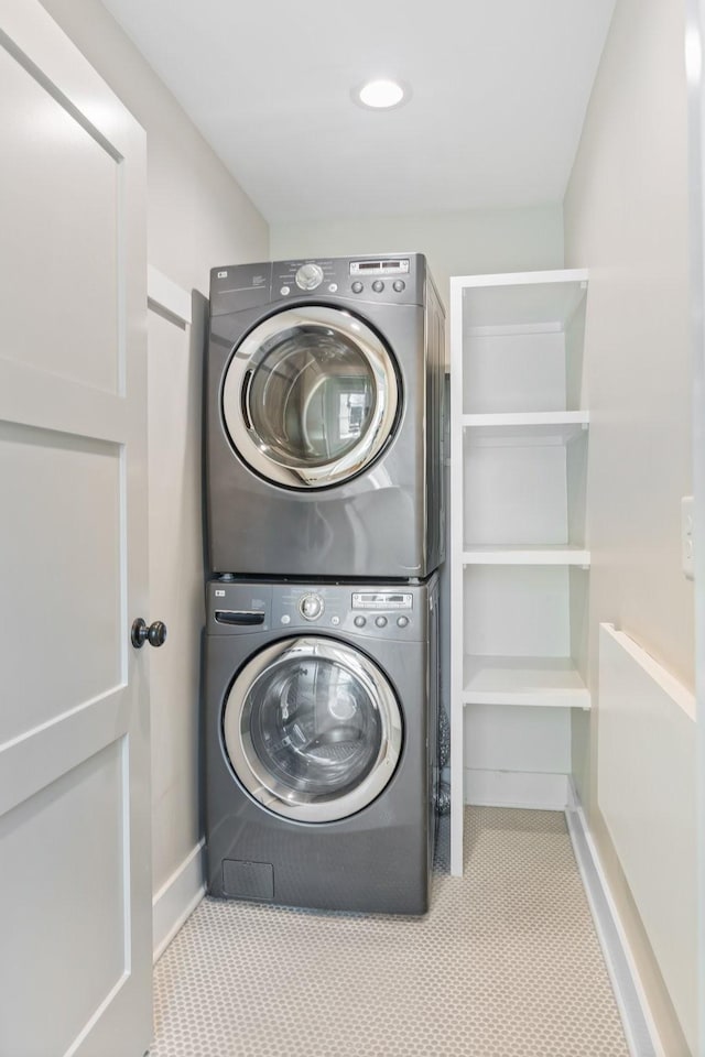 laundry area featuring laundry area, stacked washer and clothes dryer, and baseboards