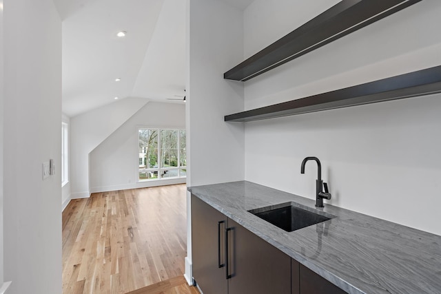 bar featuring baseboards, lofted ceiling, recessed lighting, a sink, and light wood-style floors