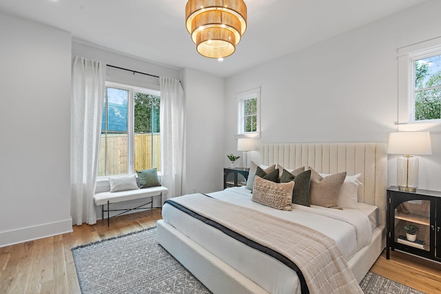 bedroom featuring multiple windows, wood finished floors, and baseboards