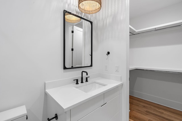 half bathroom featuring toilet, wood finished floors, and vanity