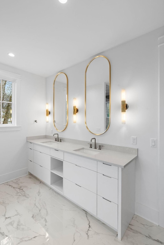 bathroom featuring a sink, baseboards, marble finish floor, and double vanity