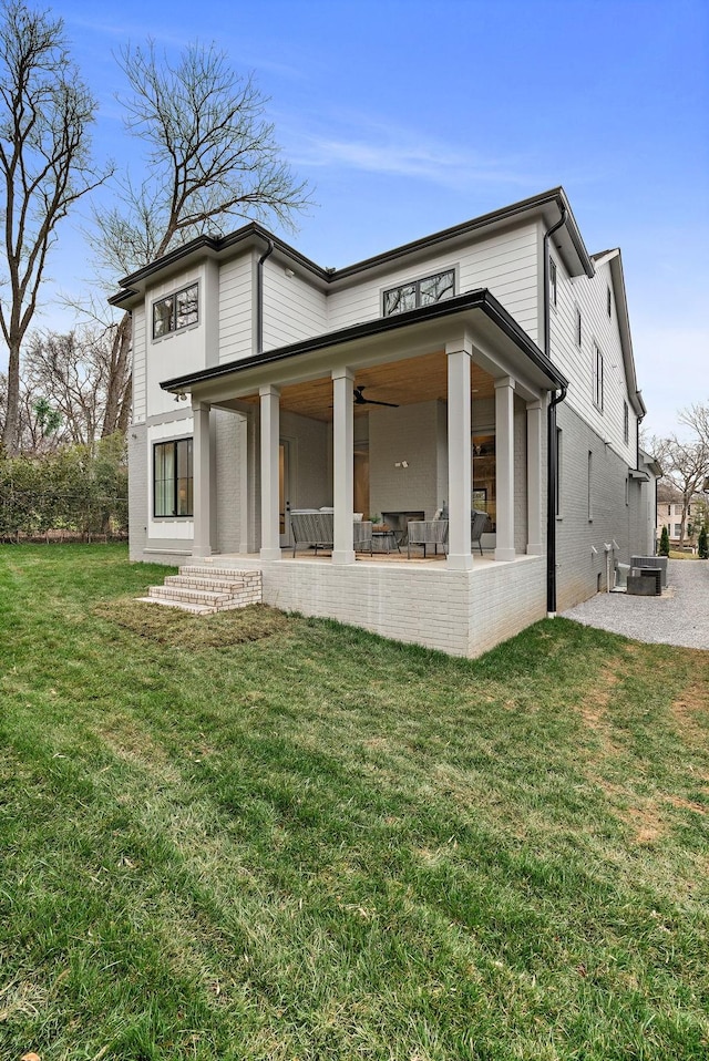 rear view of house featuring a yard, cooling unit, brick siding, and a patio