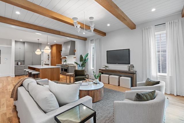 living area with beamed ceiling, light wood finished floors, recessed lighting, and a wealth of natural light