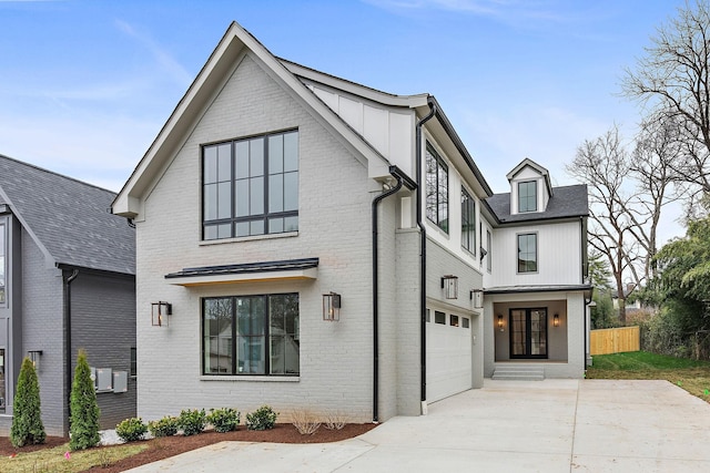 view of front facade with board and batten siding, concrete driveway, fence, and brick siding