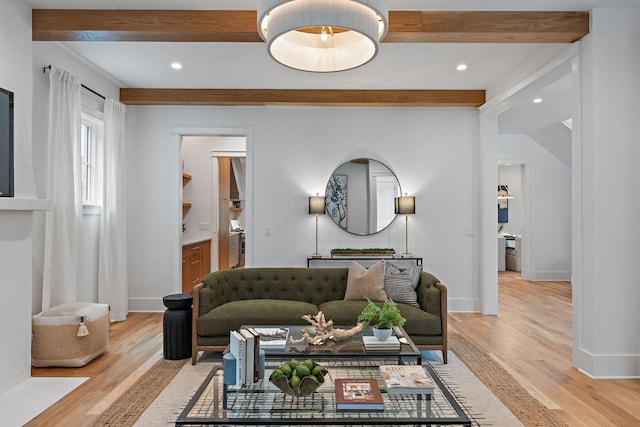 living room featuring beamed ceiling, baseboards, and light wood-style flooring