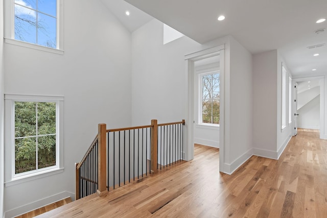 hallway featuring visible vents, baseboards, an upstairs landing, recessed lighting, and light wood-style flooring