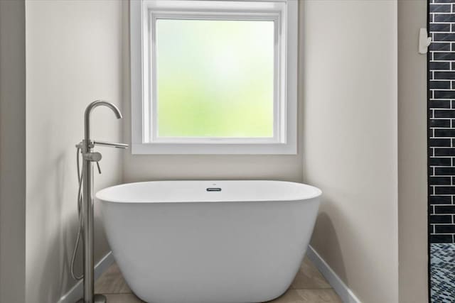 full bath with baseboards, a soaking tub, and tile patterned flooring