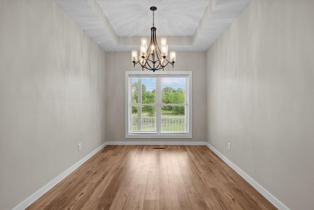 unfurnished dining area featuring a chandelier, wood finished floors, and baseboards