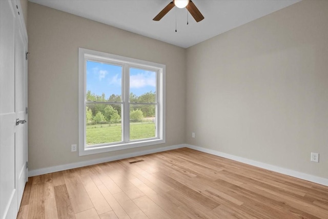 empty room featuring healthy amount of natural light, light wood-style floors, ceiling fan, and baseboards