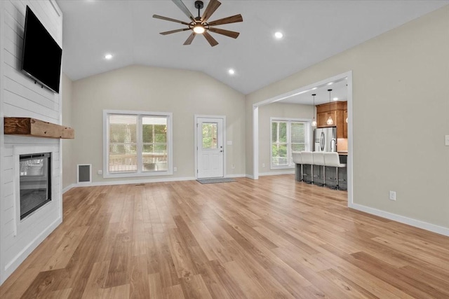 unfurnished living room featuring a large fireplace, a ceiling fan, light wood-style flooring, lofted ceiling, and baseboards