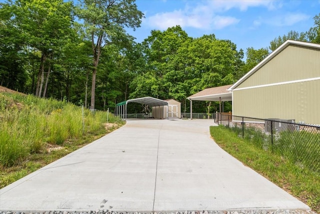 view of side of home featuring a shed, concrete driveway, fence, an outdoor structure, and a carport