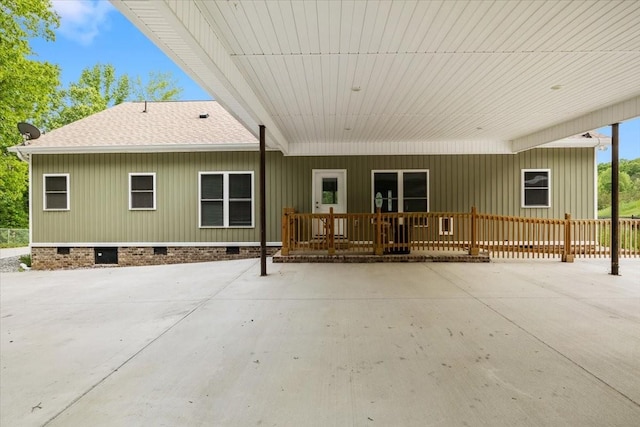 back of house with crawl space, roof with shingles, an attached carport, and a porch