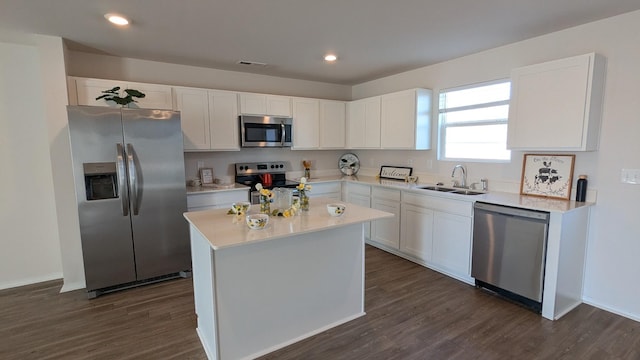 kitchen with dark wood-style floors, a sink, stainless steel appliances, light countertops, and white cabinetry