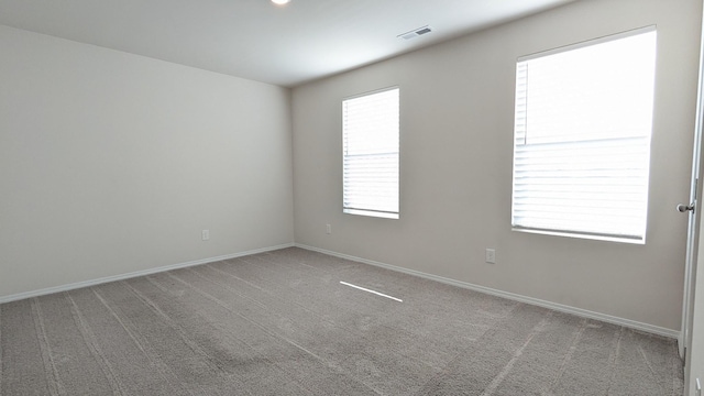 carpeted empty room featuring visible vents and baseboards